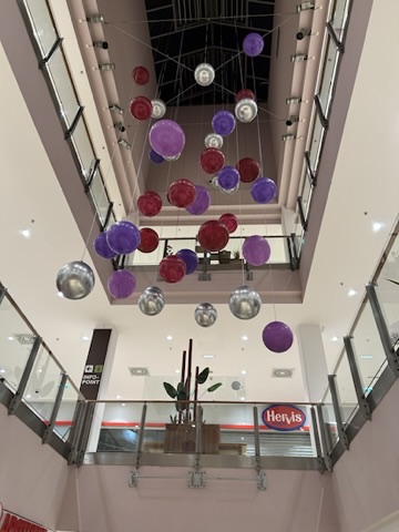 Schwebende Ballonkugeln in Lila, Rot und Silber in einem Atrium