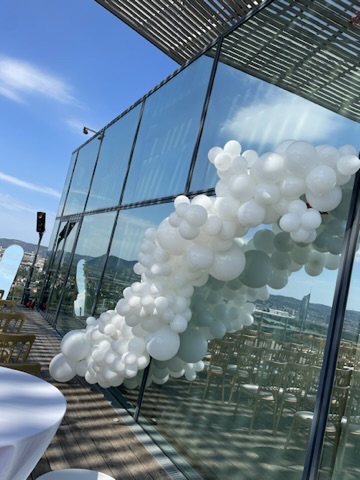 Weiße Balloninstallation an einer Glasfassade auf einer Dachterrasse