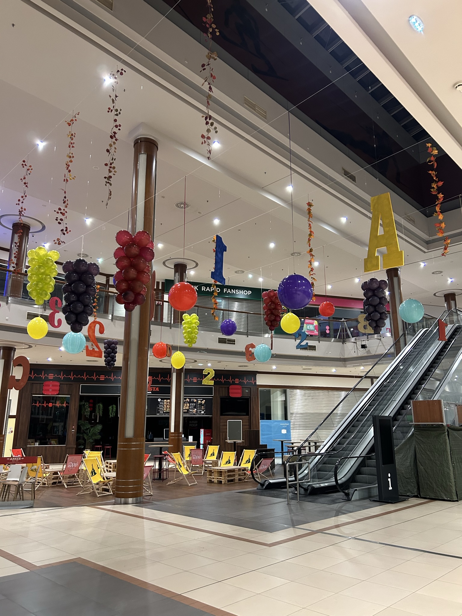 Bunte hängende Ballondekoration in einem Einkaufszentrum mit Zahlen und Traubenformen