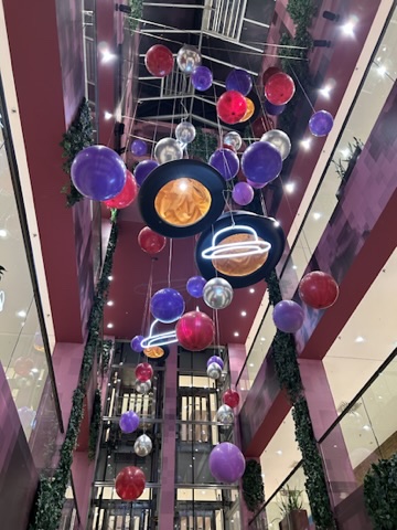 Weltraumartige Balloninstallation mit Planetenformen in einem Atrium