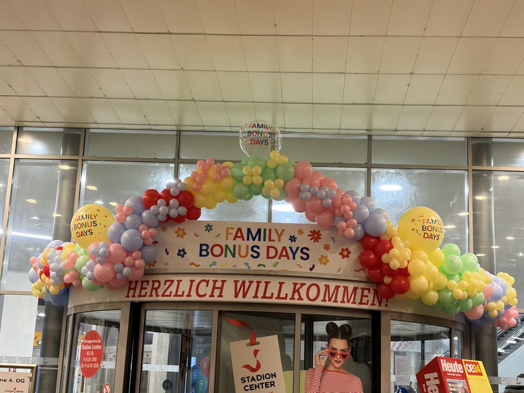Bunter Willkommensbogen für Family Bonus Days am Eingang eines Einkaufszentrums