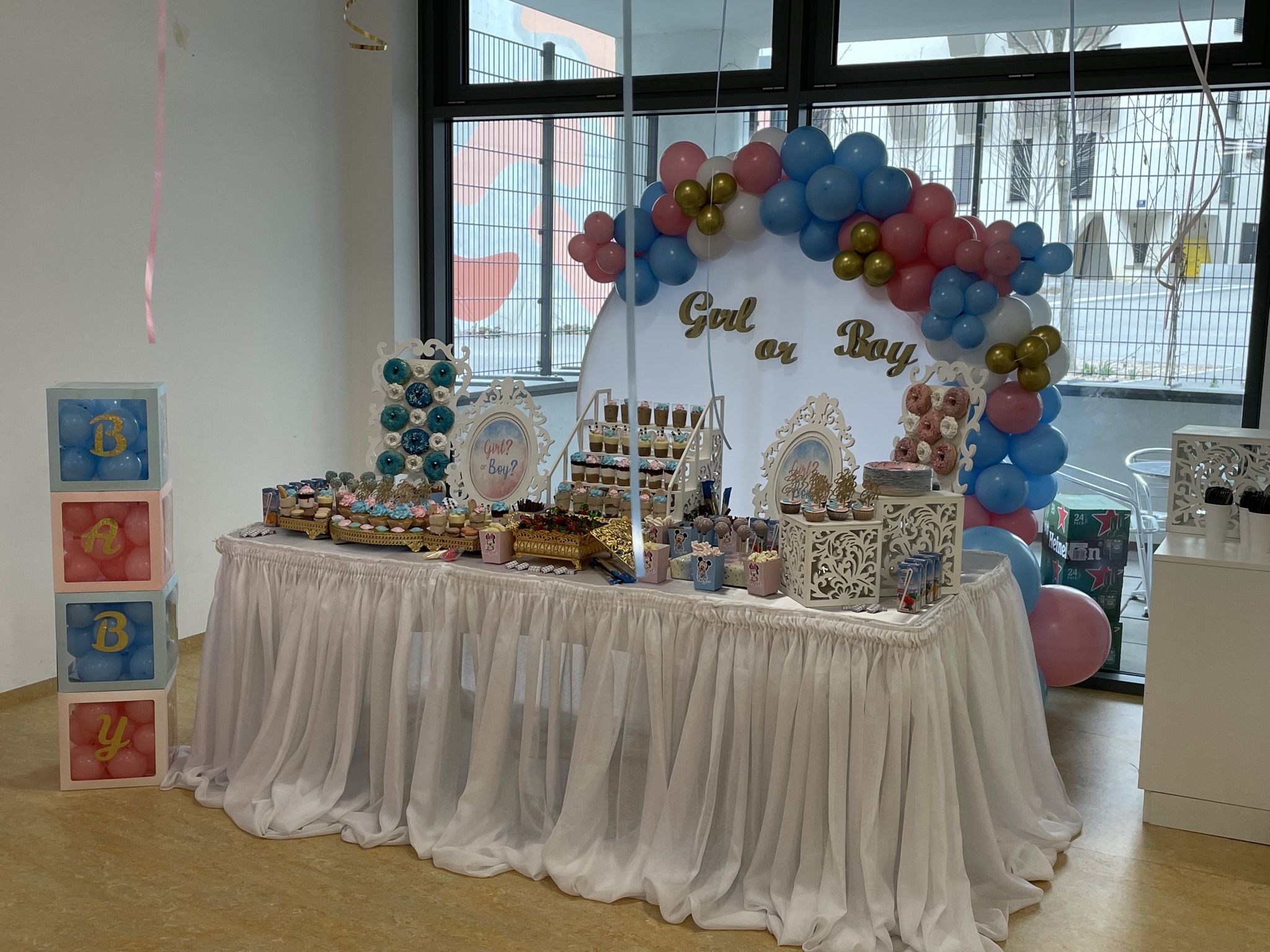 Desserttisch für private Feier mit rosa-blauem Ballonbogen und dekorativen Details